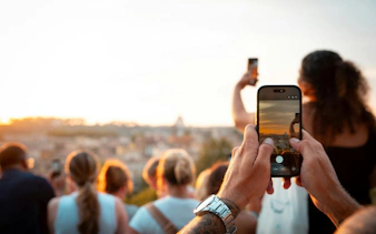 Tourists capturing sunset views of Rome on a panoramic golf cart tour.