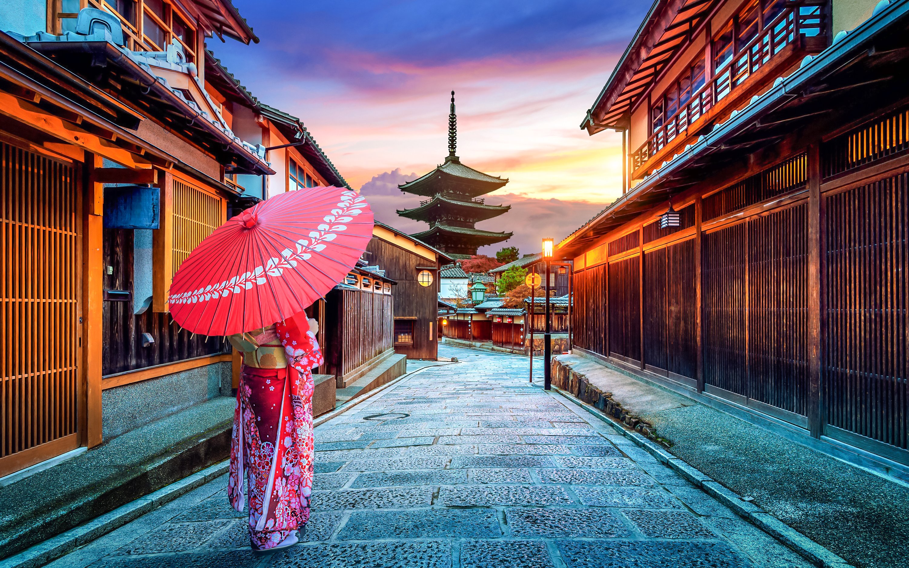 Traditional street in Sannenzaka, Kyoto, with wooden houses and a pagoda at sunset.