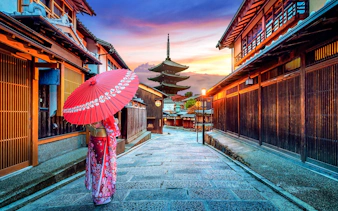 Traditional street in Sannenzaka, Kyoto, with wooden houses and a pagoda at sunset.