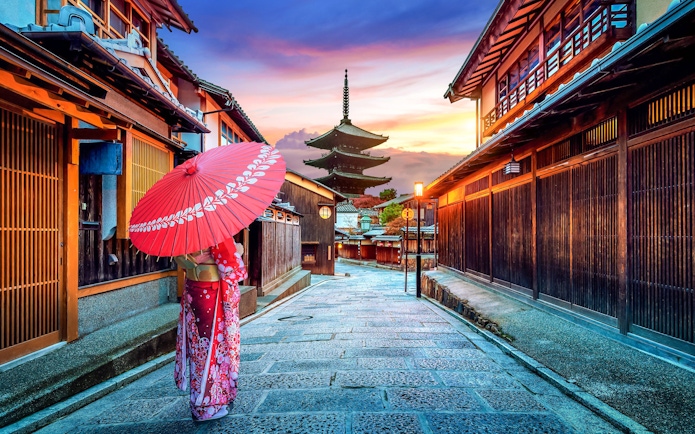 Traditional street in Sannenzaka, Kyoto, with wooden houses and a pagoda at sunset.