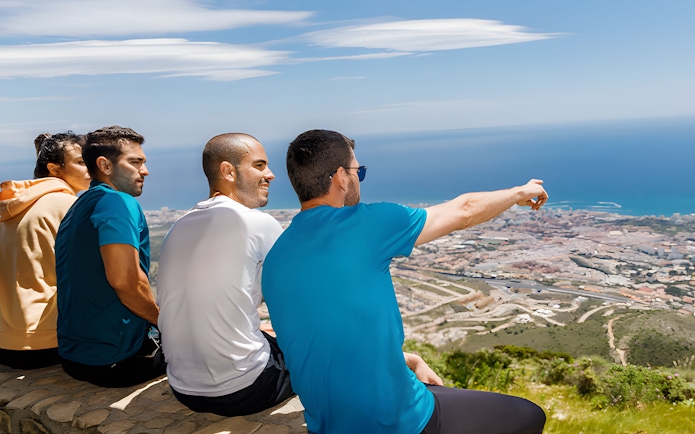 Group enjoying the view from Mount Calamorro summit, overlooking Benalmádena and the sea, Spain.