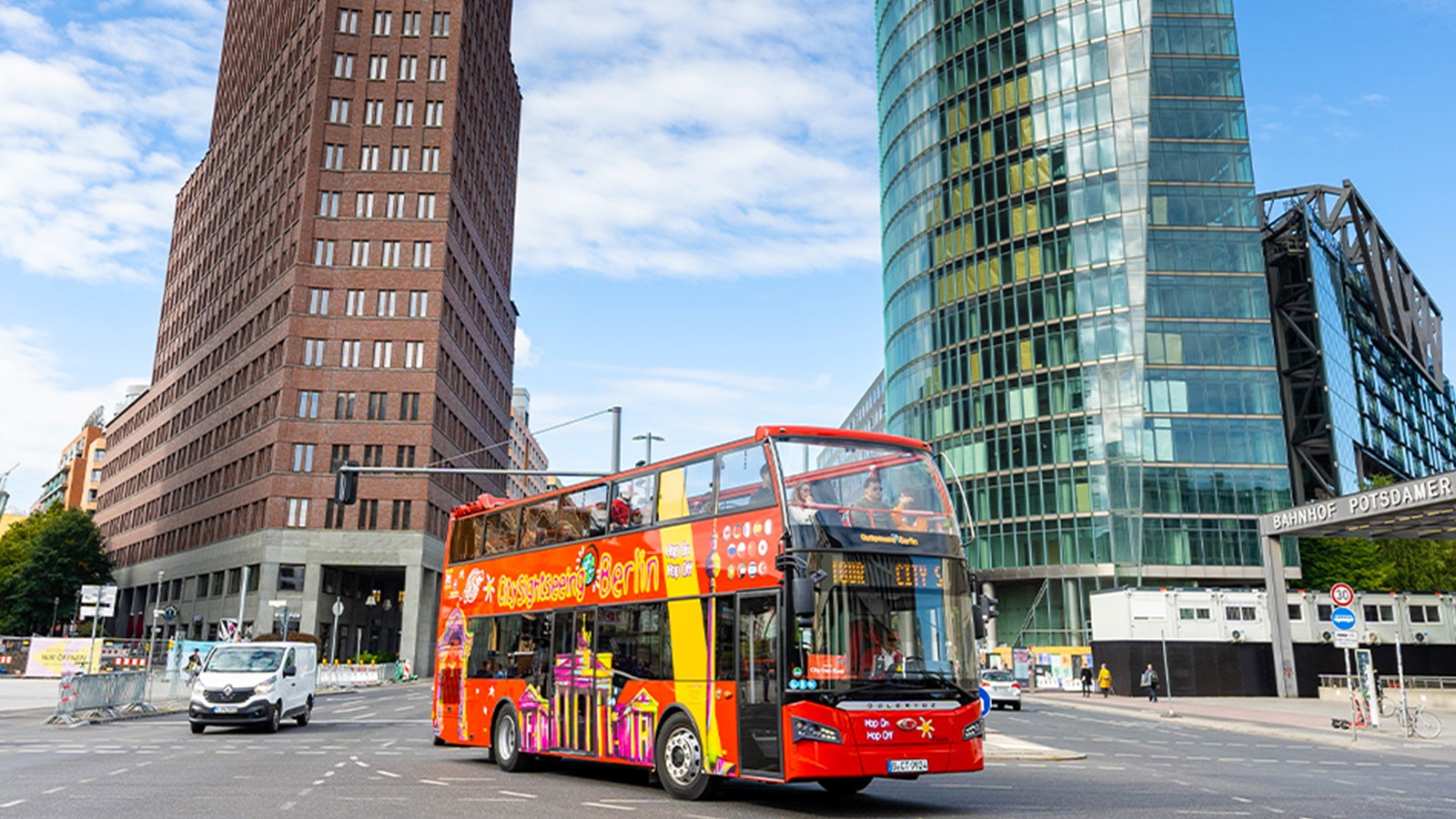 Red double-decker bus on Berlin Hop On & Hop Off tour passing Brandenburg Gate.