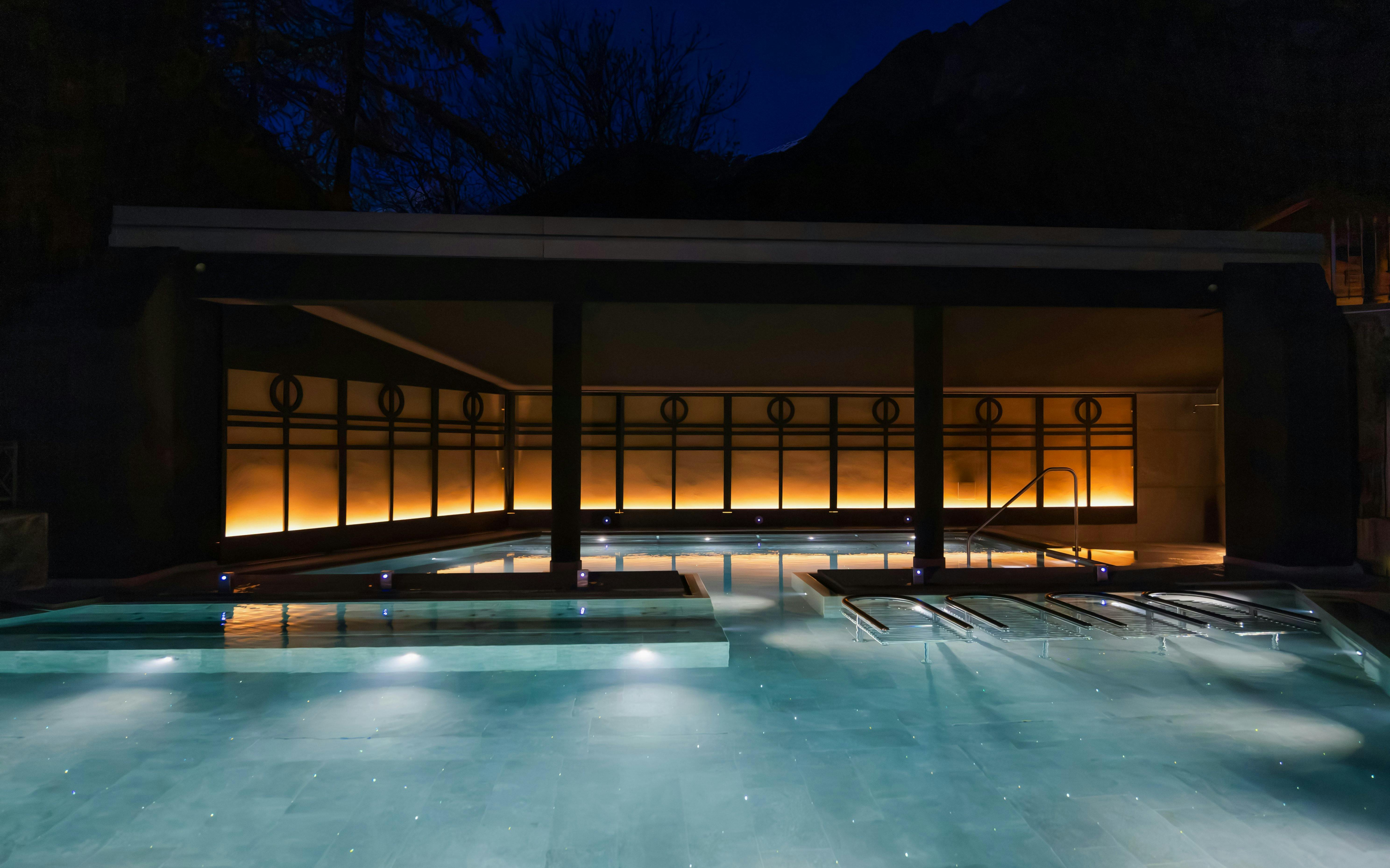 Outdoor thermal pool at QC Terme Bagni Nuovi di Bormio illuminated at night.