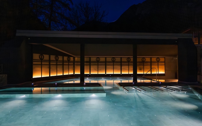 Outdoor thermal pool at QC Terme Bagni Nuovi di Bormio illuminated at night.