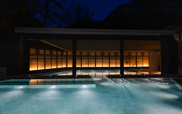Outdoor thermal pool at QC Terme Bagni Nuovi di Bormio illuminated at night.