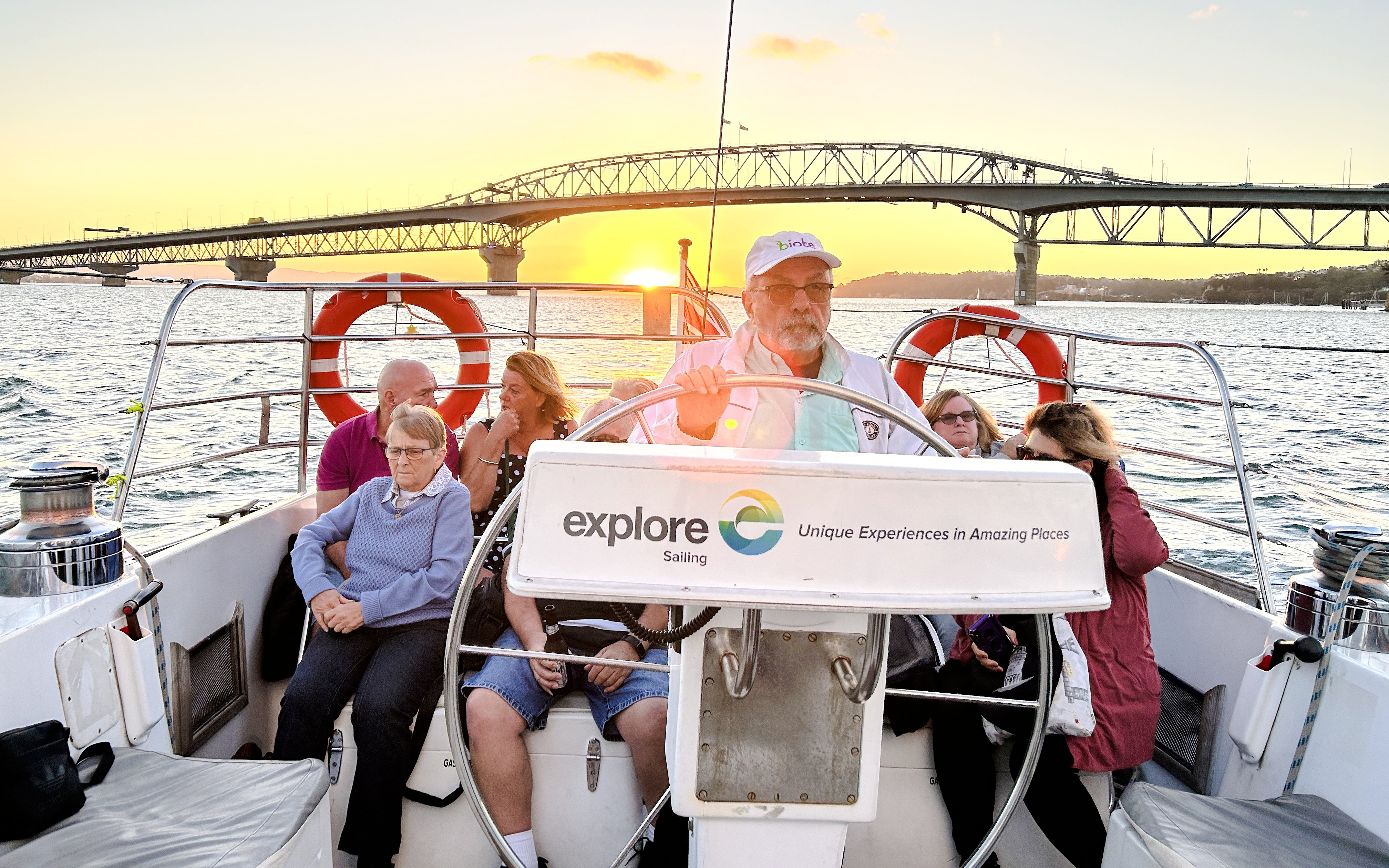 Auckland Harbour dinner cruise with guests enjoying sunset views near the bridge.