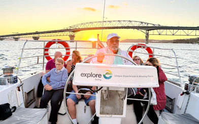 Auckland Harbour dinner cruise with guests enjoying sunset views near the bridge.