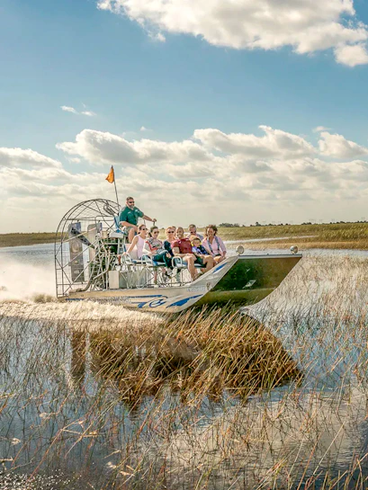 Airboat tour through the Florida Everglades with passengers enjoying the ride.