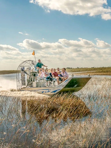 Airboat tour through the Florida Everglades with passengers enjoying the ride.