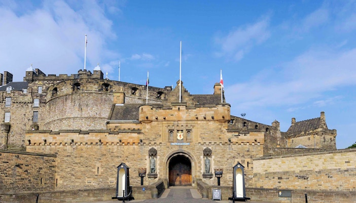 Entrance of Edinburgh Castle with stone walls and flags.