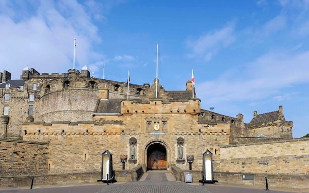 Entrance of Edinburgh Castle with stone walls and flags.