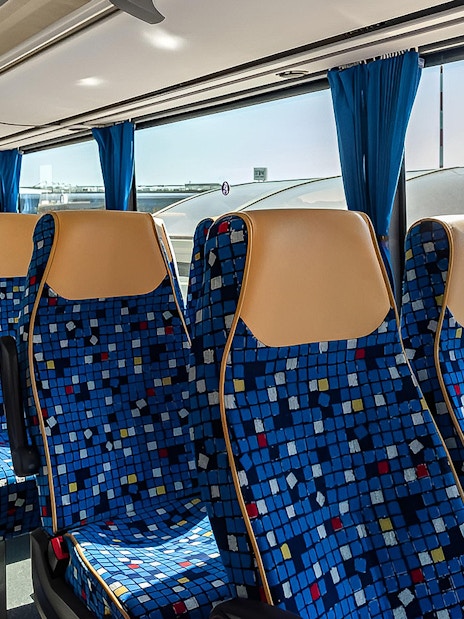 Autostradale Airport Transfer bus seating arrangement with blue patterned seats.