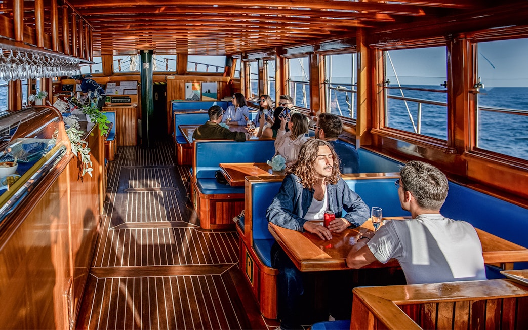 People enjoying a meal inside a catamaran with ocean views in Barcelona.