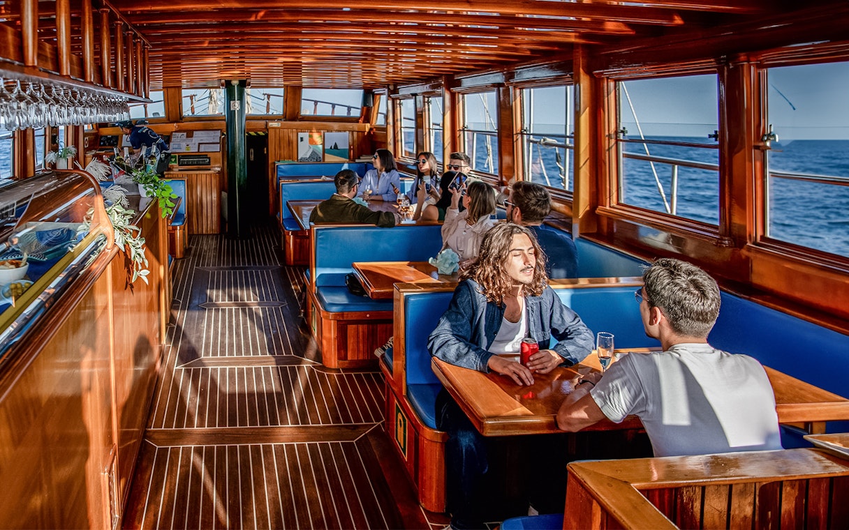 People enjoying a meal inside a catamaran with ocean views in Barcelona.