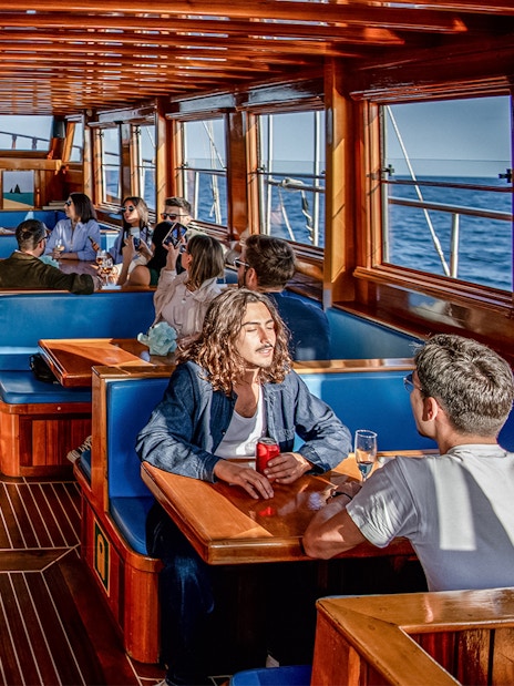 People enjoying a meal inside a catamaran with ocean views in Barcelona.