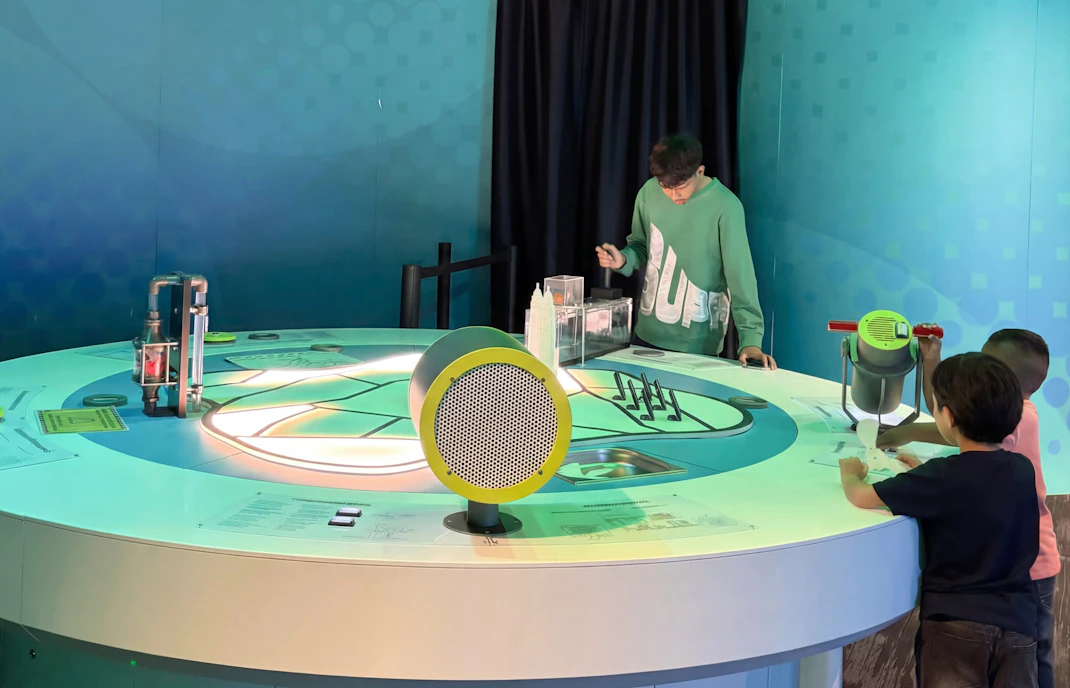 Interactive exhibit at Petrosains Science Centre with children exploring a circular display.