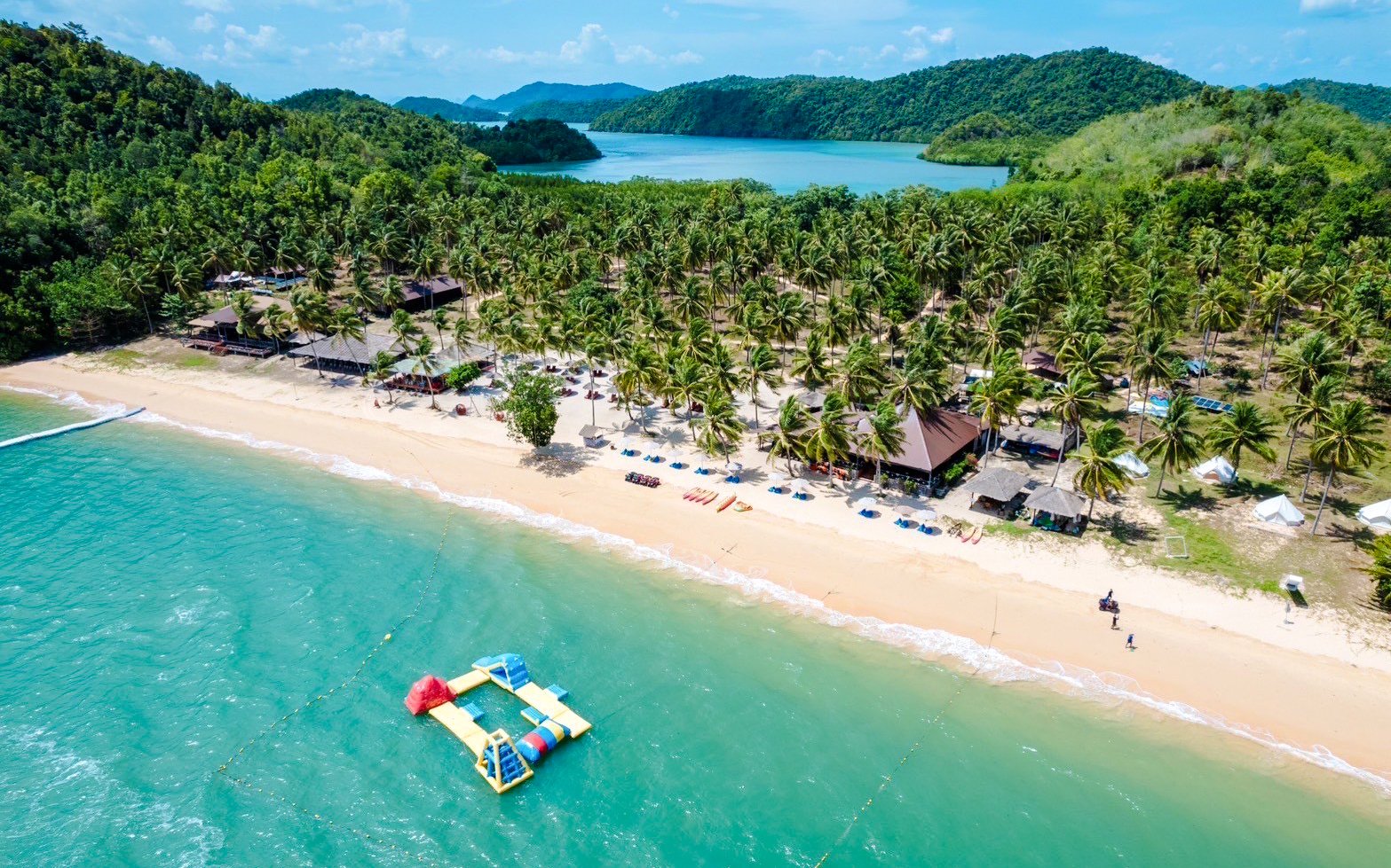 Aerial view of a tropical beach with palm trees and inflatable water park at Phang Nga Bay.