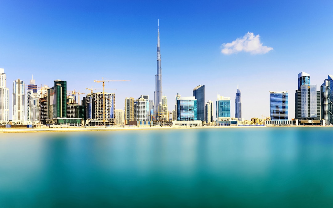 Wide angle view of Burj Khalifa and Dubai skyline across the water.