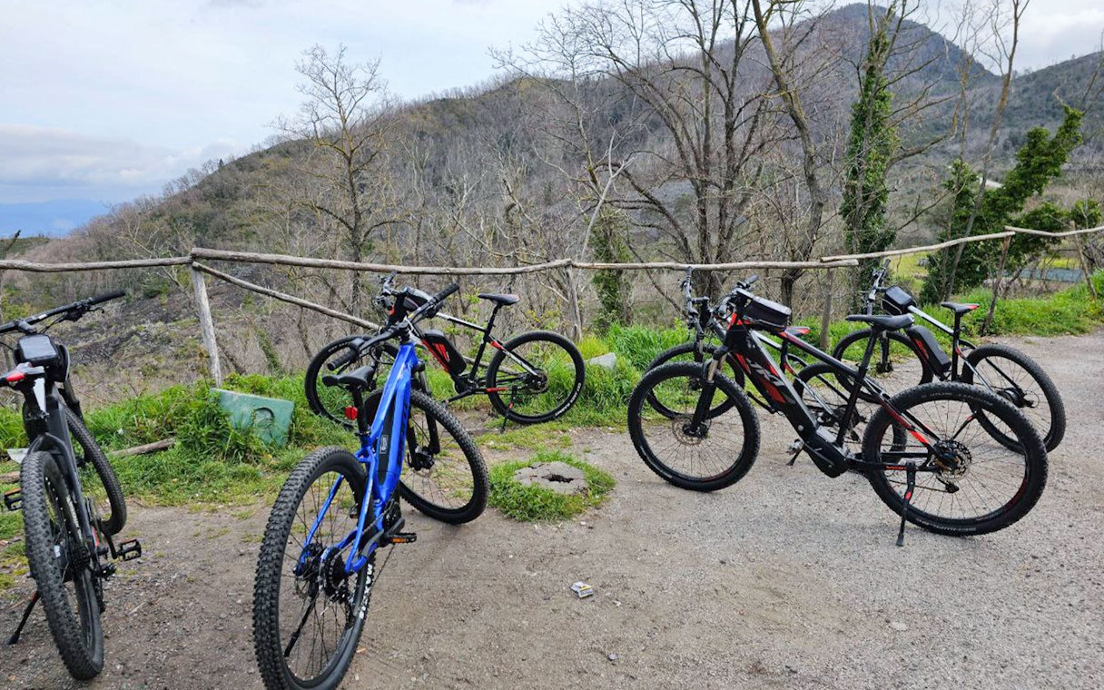 E-bikes parked on a trail with Mount Vesuvius in the background during a guided tour from Sorrento.