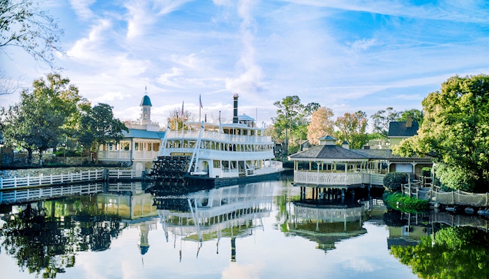 Liberty Square Riverboat on the water at Walt Disney World, Orlando, surrounded by trees and buildings.