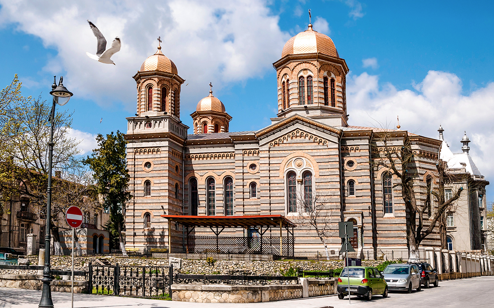 Orthodox Cathedral of Saints Peter and Paul in Constanta with copper domes and a seagull flying above.