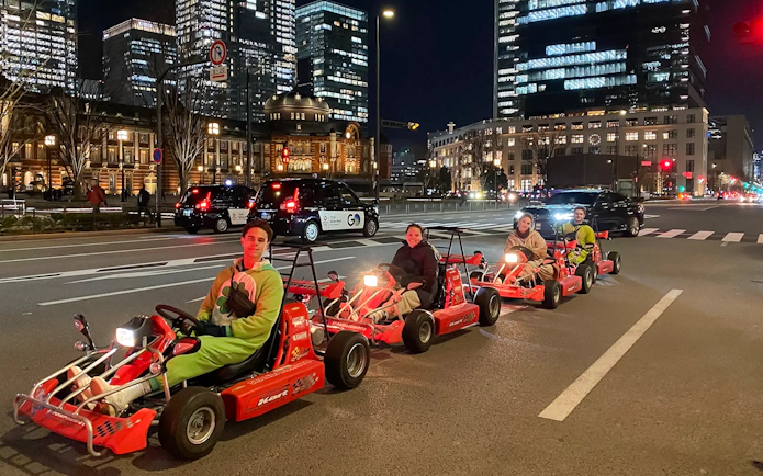 People driving go-karts on Akihabara streets in Tokyo at night.