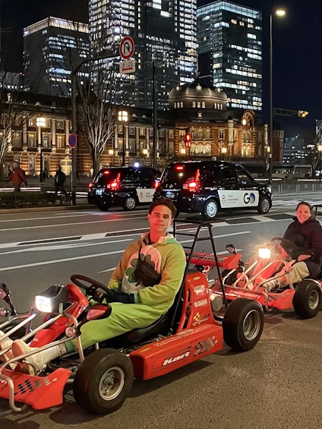 People driving go-karts on Akihabara streets in Tokyo at night.