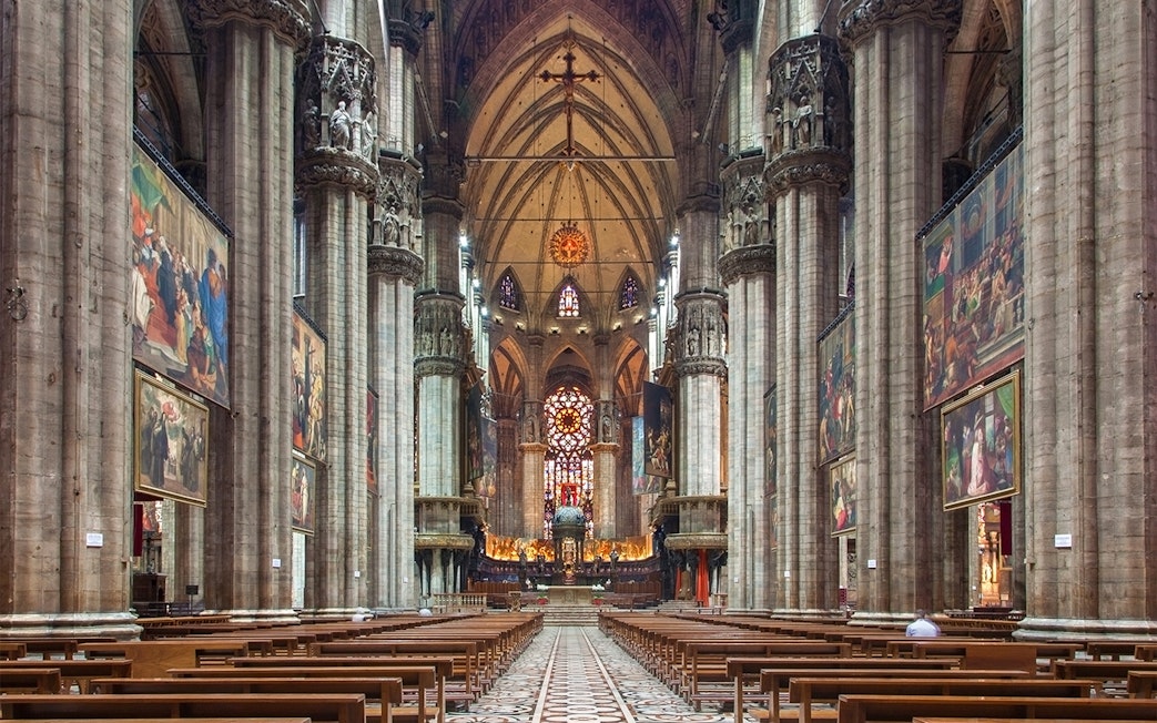 Interior of Milan Duomo with stained glass windows and ornate columns.
