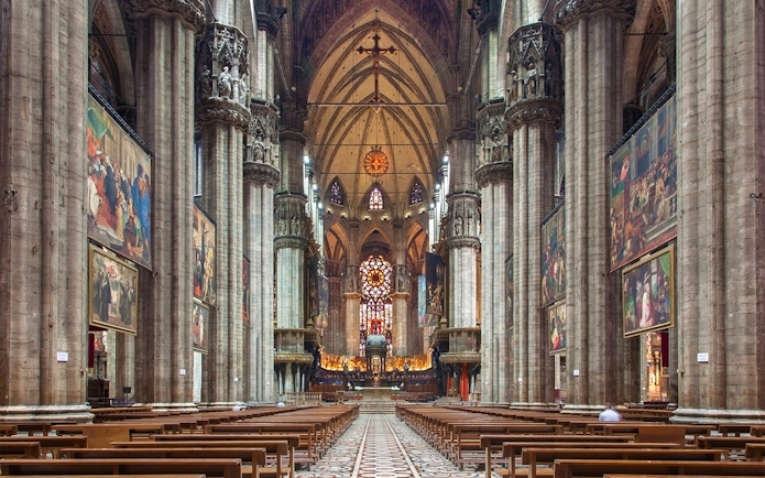 Interior of Milan Duomo with stained glass windows and ornate columns.
