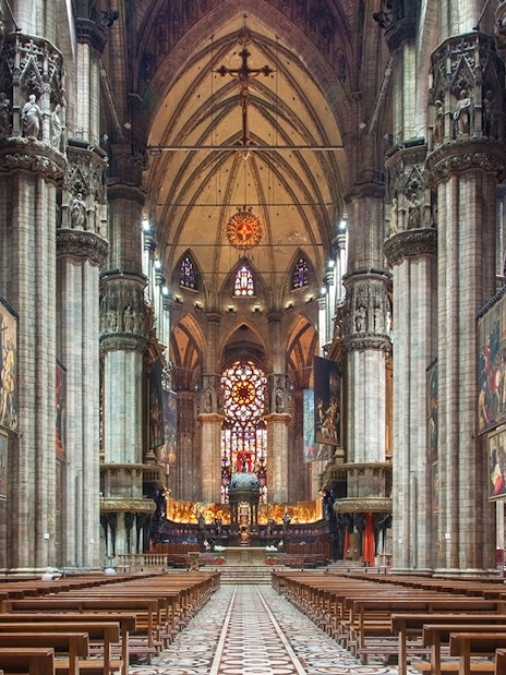 Interior of Milan Duomo with stained glass windows and ornate columns.