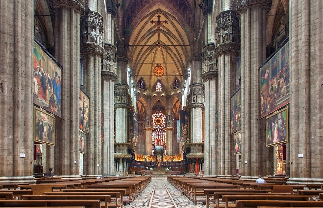 Interior of Milan Duomo with stained glass windows and ornate columns.