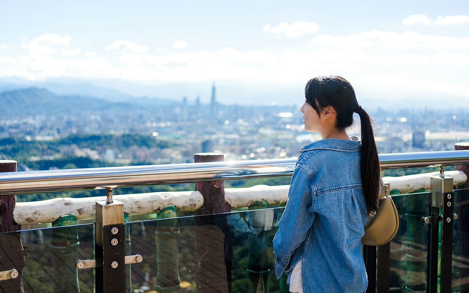 Woman enjoying city view from Taipei 101 observation deck.