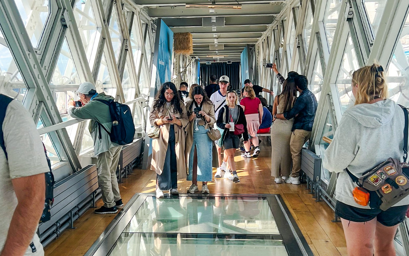 Visitors walking on the glass walkway inside Tower Bridge, London.
