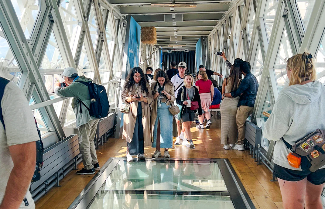 Visitors walking on the glass walkway inside Tower Bridge, London.