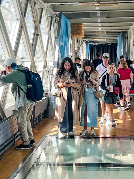 Visitors walking on the glass walkway inside Tower Bridge, London.