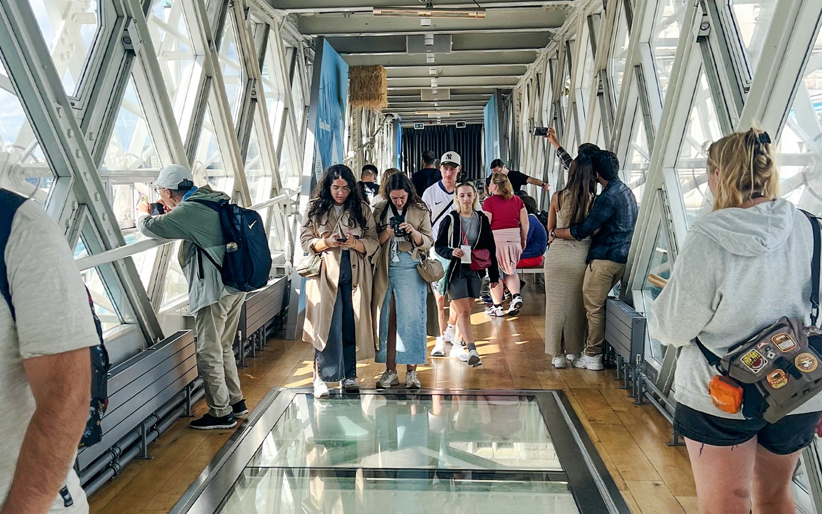 Visitors walking on the glass walkway inside Tower Bridge, London.