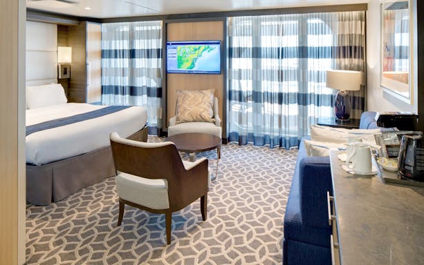 Luxurious cabin interior on Anthem of the Seas, featuring a bed, seating area, and ocean view.
