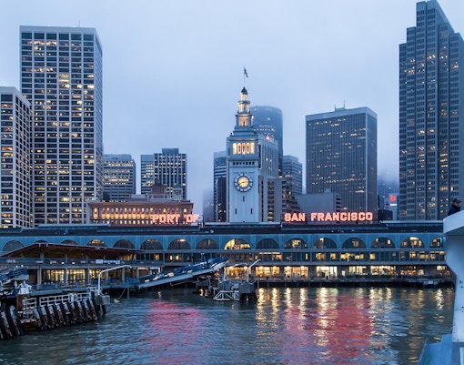 Ferry approaching Pier 39 with San Francisco skyline in the evening.