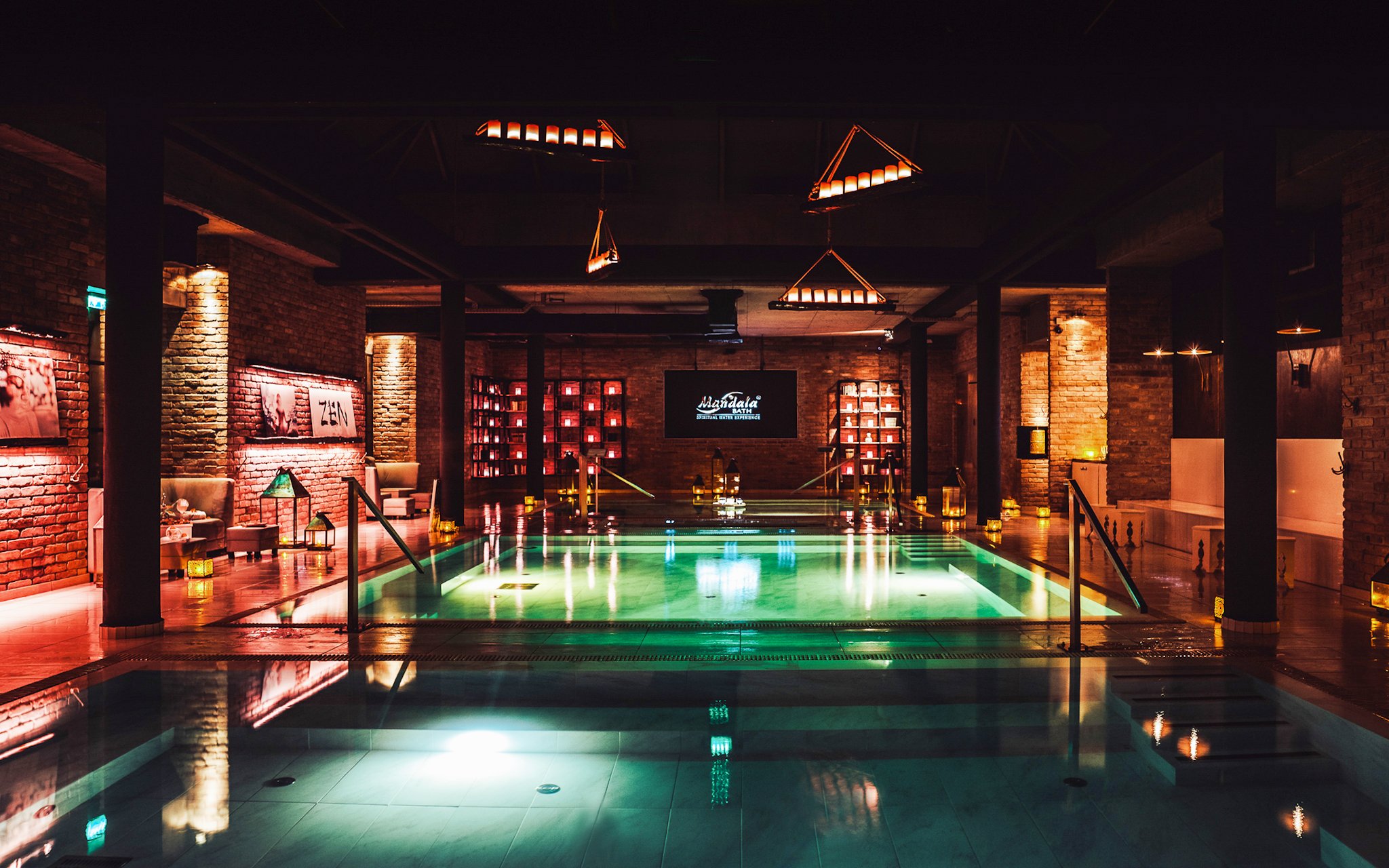 Luxurious indoor pool area at Mandala Day Spa with ambient lighting and brick walls.