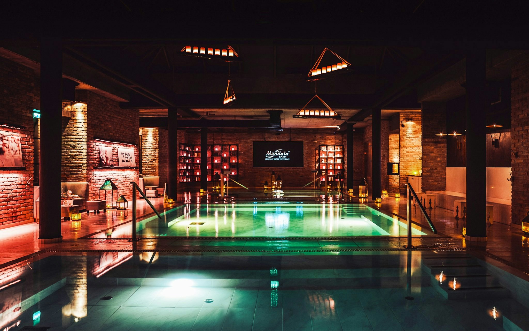 Luxurious indoor pool area at Mandala Day Spa with ambient lighting and brick walls.
