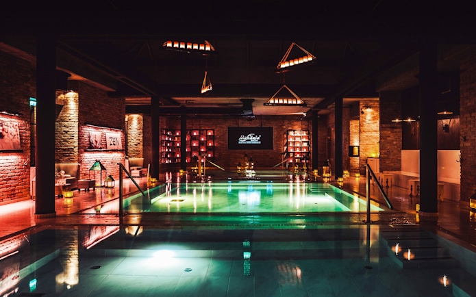 Luxurious indoor pool area at Mandala Day Spa with ambient lighting and brick walls.