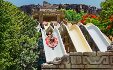 Visitors on a water slide at Aqualand Maspalomas, surrounded by lush greenery.