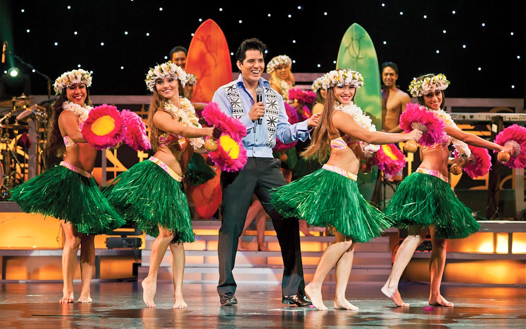Dancers performing hula at Rock-A-Hula Show with surfboards in the background.