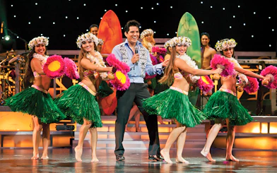 Dancers performing hula at Rock-A-Hula Show with surfboards in the background.