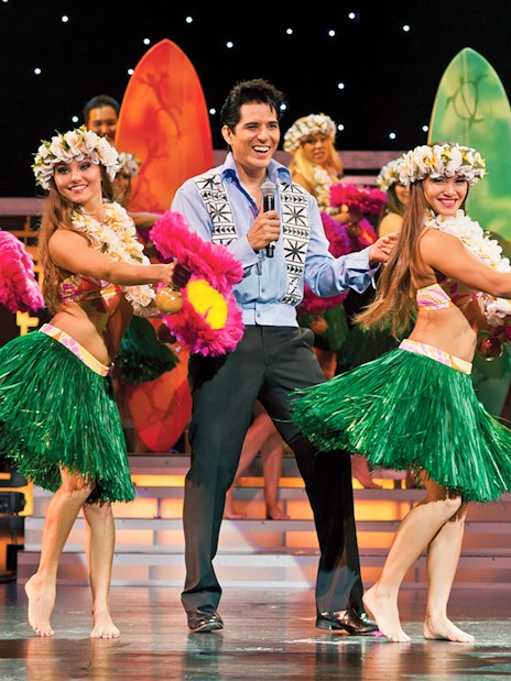 Dancers performing hula at Rock-A-Hula Show with surfboards in the background.