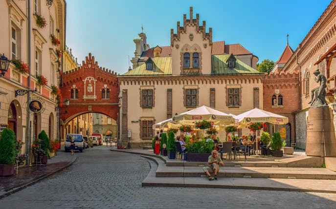 Krakow Old Town street with historic buildings and outdoor café near Market Square.