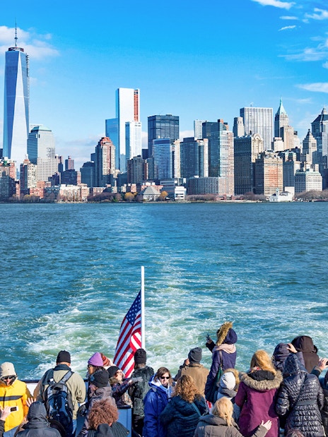 Tourists on a ferry with New York City skyline in the background.