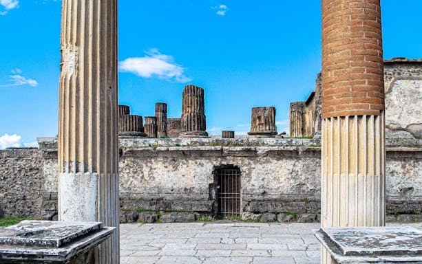 Ancient columns and ruins in Pompeii under a clear blue sky.