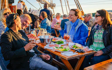 Group enjoying dinner on a boat during a summer evening cruise in Oslo.