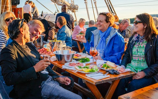 Group enjoying dinner on a boat during a summer evening cruise in Oslo.